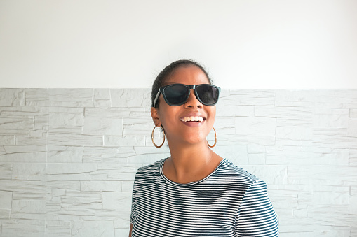 Young African-American woman with stylish sunglasses, standing facing away