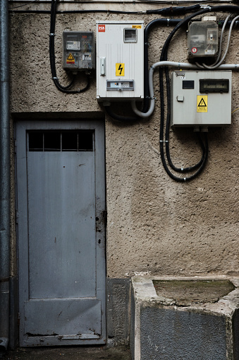 Oradea, Romania - November 26, 2016: A close view of a communist apartment building with an old maintenance door near electrical boxes and transformers.