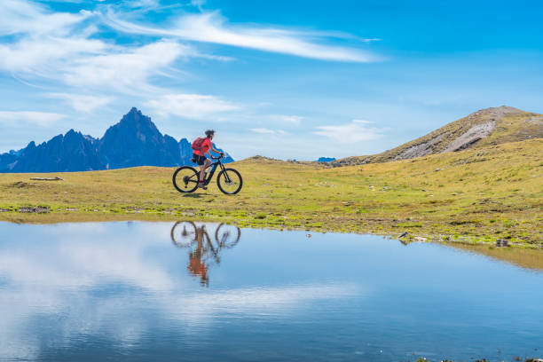 山の湖に反射電気マウンテンバイクの素敵な女性 - tranquil scene trentino european alps dolomites ストックフォトと画像