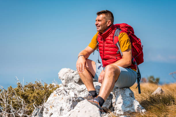 istock Adult man with back pack sitting on a rock in mountains 1272579014