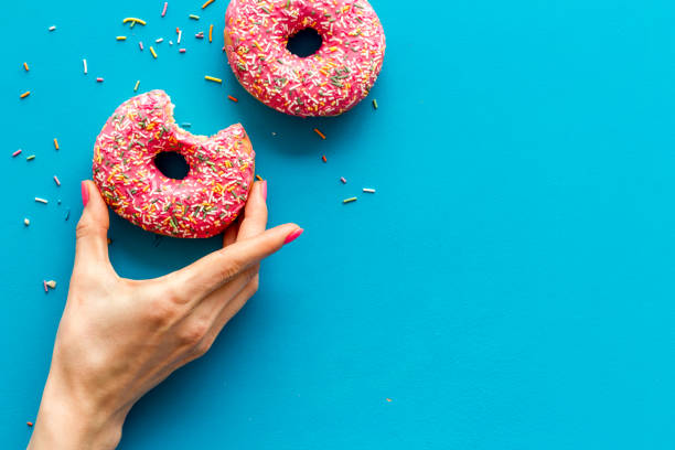 istock Hand holding glazed donut swith sprinkles, above view 1272582996
