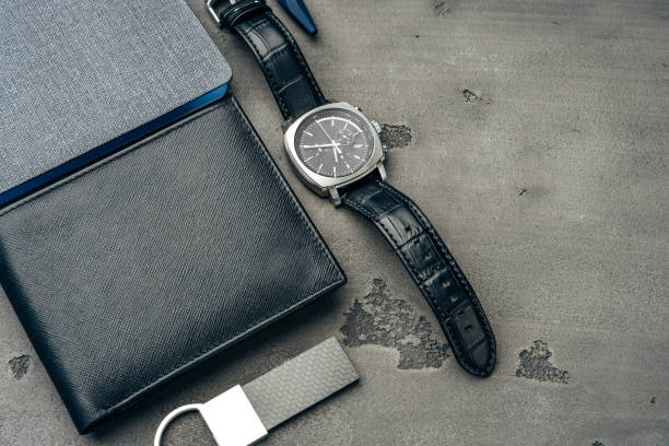 istock Businessman's accessories including notepad, watch and purse on dark grey background 1272584090