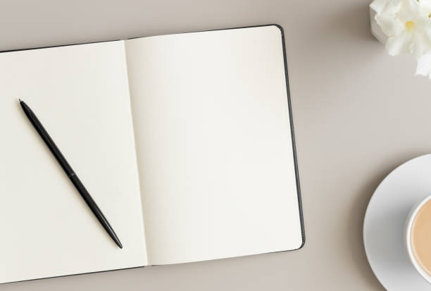 istock Open notebook mockup with a cup of coffee and oleander on a beige table. 1272585233
