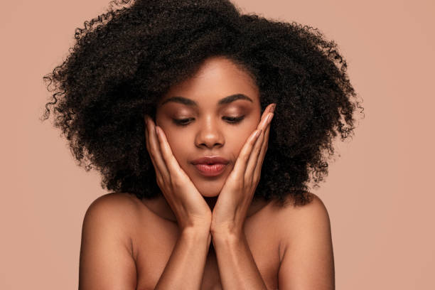 istock Young female model with perfect dark skin touching face 1272585271