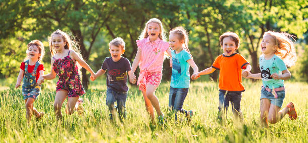 Large group of kids, friends boys and girls running in the park on sunny summer day in casual clothes . stock photo