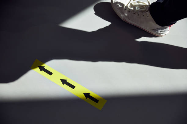 Close-up of dress shoes, striped socks and fashionable skinny trousers of businessman walking with his shadow on modern city sidewalk