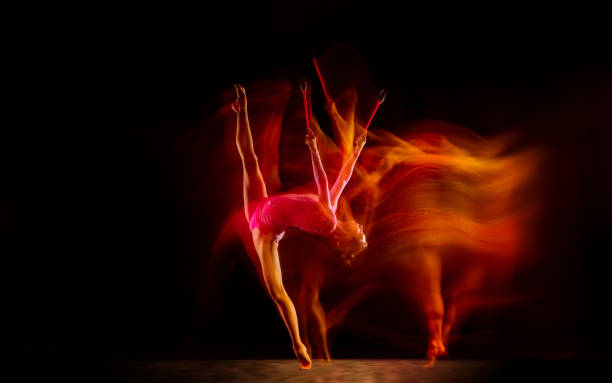istock Young flexible female gymnast isolated on black studio background in mixed light, 1272587181