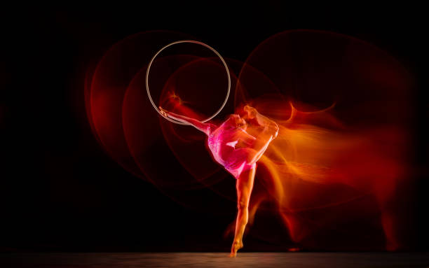 istock Young flexible female gymnast isolated on black studio background in mixed light, 1272587182