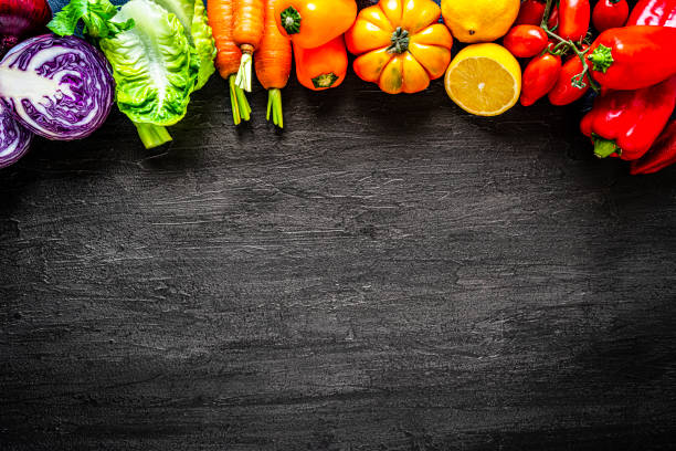 istock Healthy rainbow colored vegetables frame on black slate background. Overhead view 1272587208