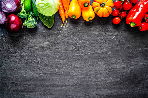 istock Healthy rainbow colored vegetables frame on black slate background. Overhead view 1272587209