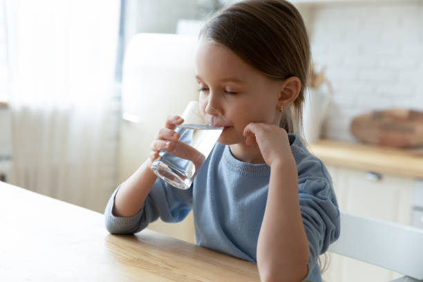 istock Thirsty small cute caucasian kid drinking water. 1272589217