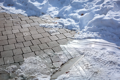 Close-up on tiled pavement covered with ice and snow.