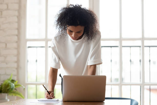 istock Biracial female employee make notes working on laptop 1272592669