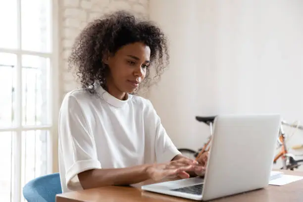 Photo of African American female employee busy working on laptop