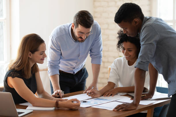 istock Smiling diverse colleagues discuss paperwork at meeting 1272592691