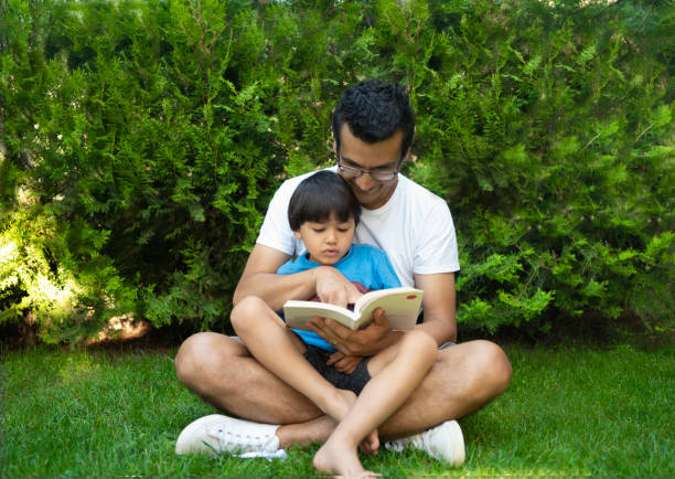 istock Boy is reading a book with his father in the garden 1272594255