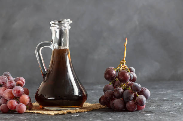botella de vidrio de vinagre balsámico de uva negra orgánica elaborado a partir de uvas frescas fermentadas. comida negra con alimentos orgánicos saludables, enfoque selectivo - balsamic vinegar fotos fotografías e imágenes de stock