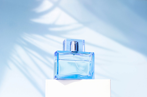 Perfume bottle on a blue background with a shadow. Stylish appearance of the product. Monochrome