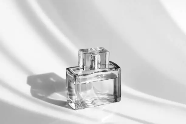 Perfume bottle on a blue background with a shadow. Stylish appearance of the product. Monochrome