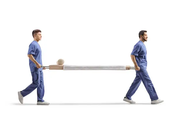 Full length profile shot of two male healthcare workers carrying an empty stretcher bed isolated on white background