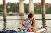 Adventurous Young Mother Paddle Boarding with Her Cute Baby Daughter