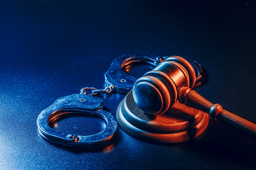 Judge gavel and handcuffs on dark black background