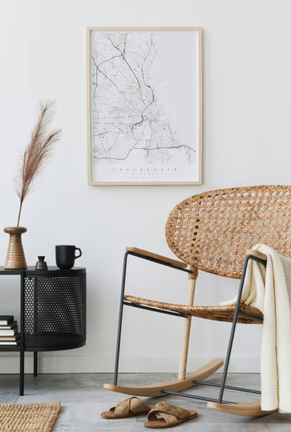istock Modern scandinavian living room interior with mock up poster frame, design commode, leaf in vase, rattan armchair, book and elegant accessories in stylish home decor. Template. 1272599648
