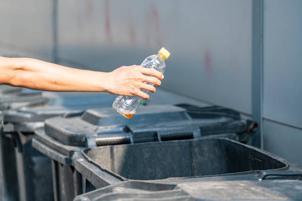 istock One hand is throwing the empty water bottle into the trash can 1272599884