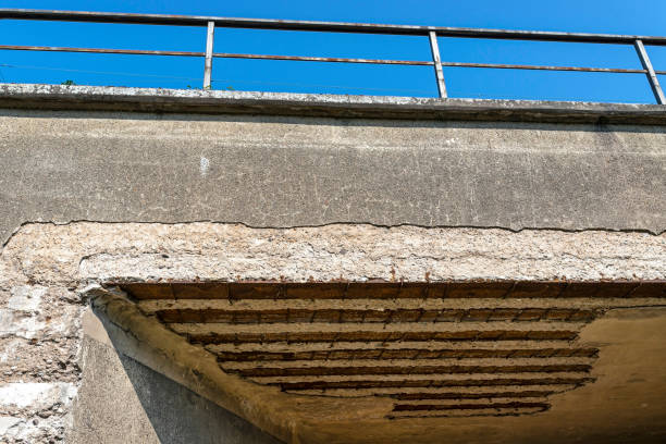 Damaged railway viaduct with cracked ceiling, visible rusty reinforcement and steel.