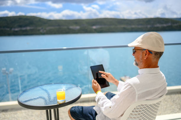 l’homme apprécie le balcon et utilisant la tablette numérique - reading beach e reader men photos et images de collection