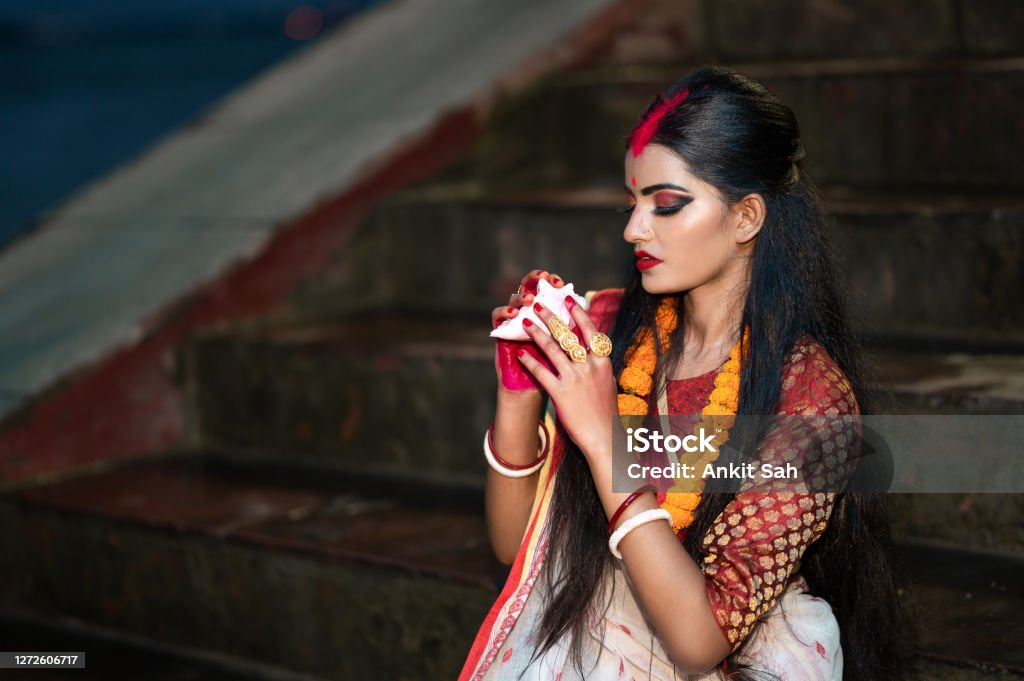 Traditional Bengali woman blowing shankha Traditional Bengali woman wearing red and white sari and blowing shankha. Durga Stock Photo