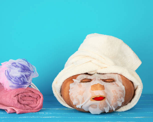 istock round orange pumpkin wrapped in a white terry towel, face mask on the surface 1272607707