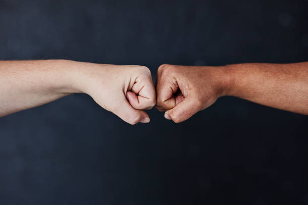 Our differences don't have to divide us Studio shot of two unrecognisable women bumping fists against a dark background womens rights photos stock pictures, royalty-free photos & images