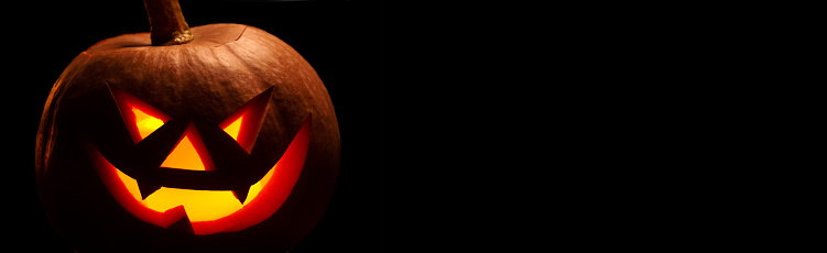 Halloween pumpkin with scary face. Jack-o-lantern in the dark. Celebration autumn holiday. Long banner