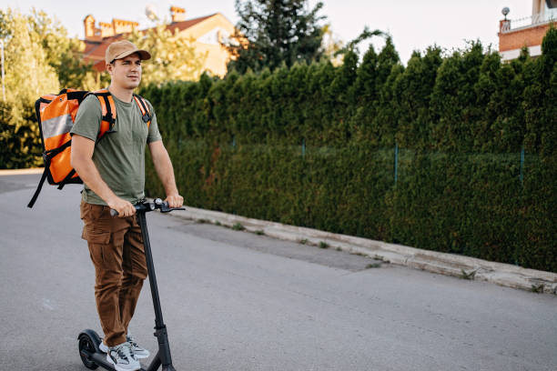 istock Young delivery man on an electric scooter delivering packages 1272612232