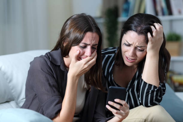 istock Sad friends or sisters crying checking smart phone 1272613648