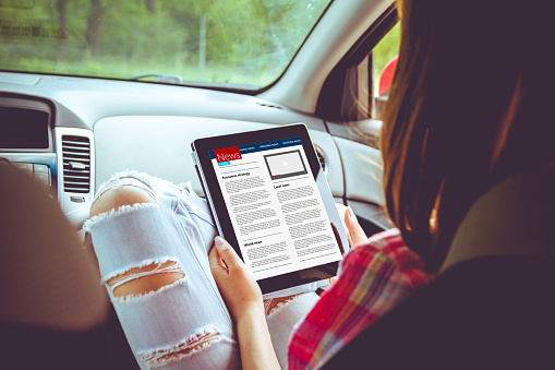 Girl with tablet in her hands in the car. Hitchhiking, car ride concept