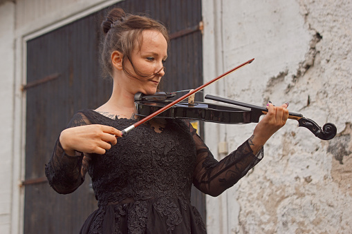 Full length portrait of a elegant musician playing an acoustic violin isolated on white background