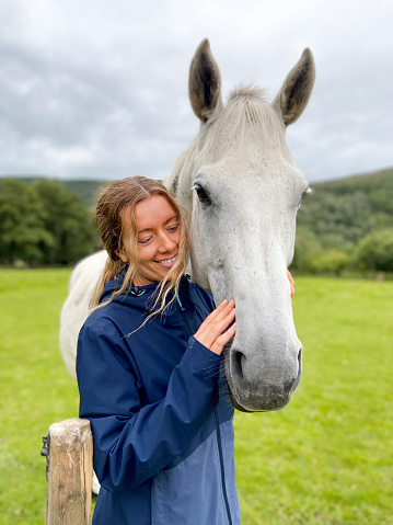 Mid-adult women standing next to a white horse in the countryside in North Yorkshire.