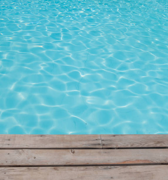 istock Blue tiles pool water ripple texture and wooden background. 1272620760