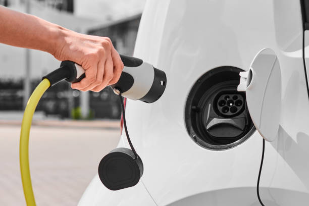 Woman unplugging a charger from an electric car socket. Eco friendly vehicle with zero emission Woman unplugging a charger from an electric car socket. Eco friendly vehicle with zero emission plugging in photos stock pictures, royalty-free photos & images