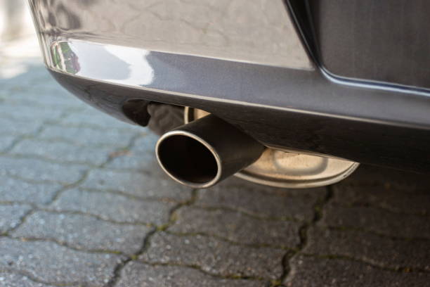 Car engine single exhaust metal tip close up shot next to rear bumper Car engine single exhaust metal tip close up shot next to rear bumper. plug adapter stock pictures, royalty-free photos & images