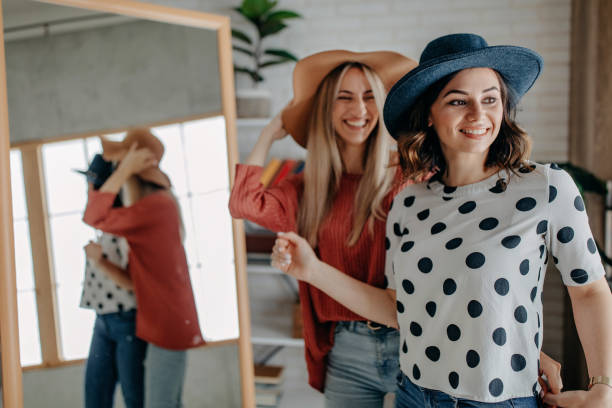 istock Two best friends playing with hat in front of mirror 1272627750