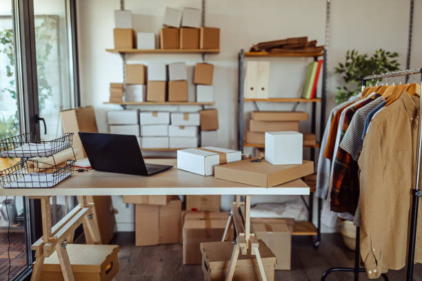 istock Laptop with cardboard boxes ready for e-commerce delivery at clothing warehouse 1272627803