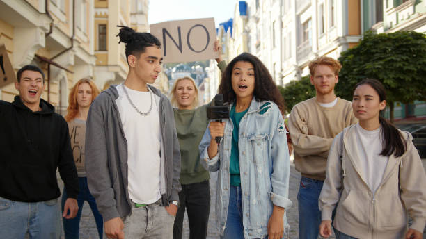 istock Journalist interviews mixed race activist in front of multiracial protest mob 1272629921