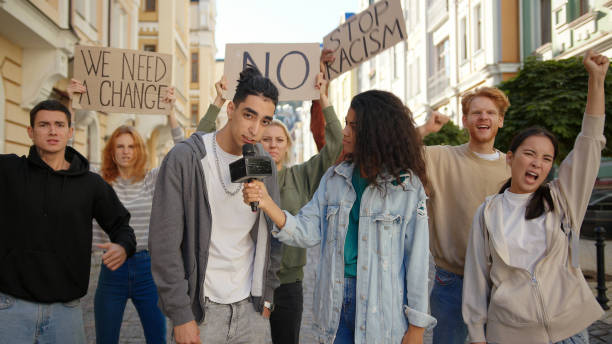 istock Journalist interviews mixed race activist in front of multiracial protest mob 1272629946