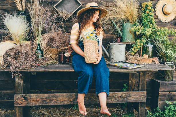 jeune femme brune dans le chapeau de paille et le tablier arrange le bouquet avec des fleurs douces de vent - autumn table setting flower photos et images de collection