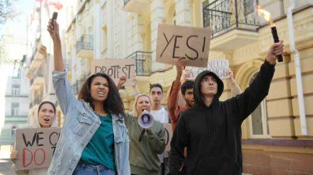 istock Angry activists protesters protesting in the city with posters, smoke bombs and fire flares 1272630932