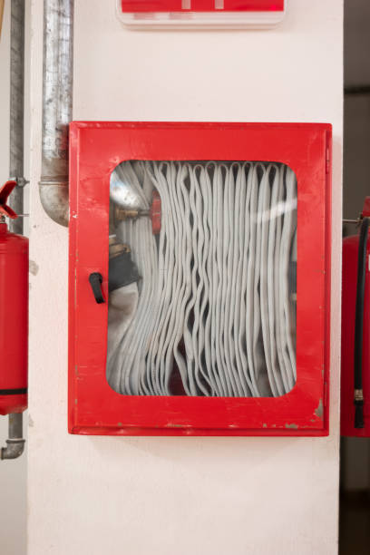 istock Fire hose mounted on factory wall in closed emergency break red box 1272632016