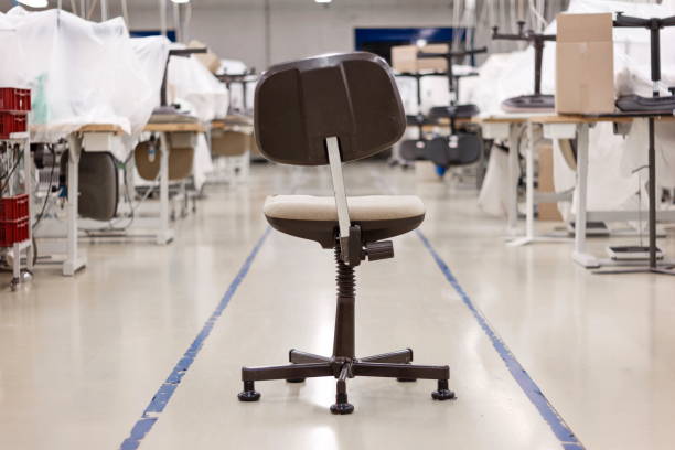 Old broken office swivel chair sitting in the middle of a closed down factory production line Old broken office swivel chair sitting in the middle of a closed down factory production line. messy vs clean desk stock pictures, royalty-free photos & images